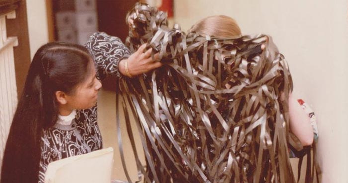 Two women holding a large pile of tangled magnetic tape