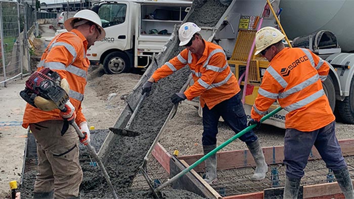 Three construction workers pouring concrete on building site