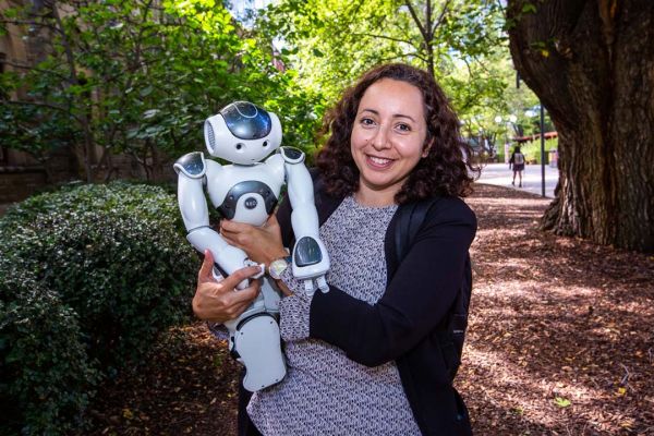 Female staff member holds a small novelty robot looking at the camera