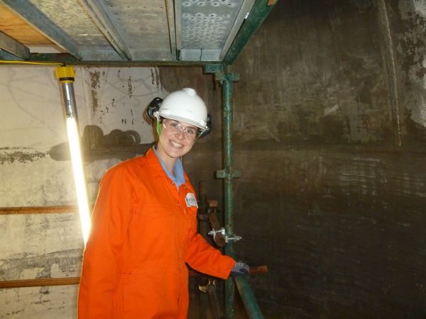 Nyssa Nair Female student in orange overalls working on construction site