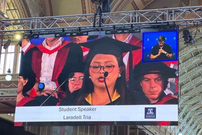 Girl on screen speaking at graduation.