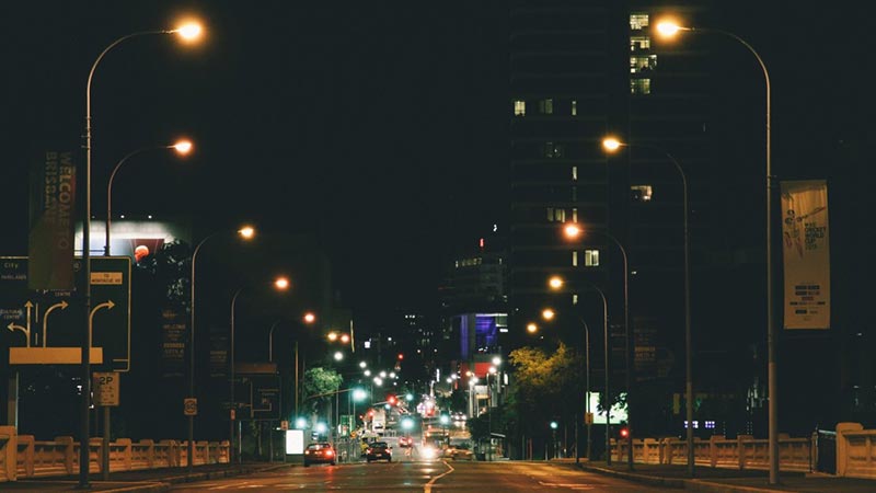 An Australian road at night with streetlights lit on either side
