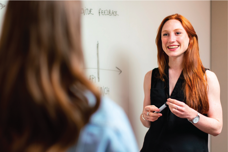 Two people having a conversation in front of a whiteboard