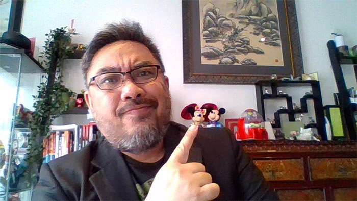 Shanton Chang in home office with objects including Mickey and Minnie Mouse figurines behind him