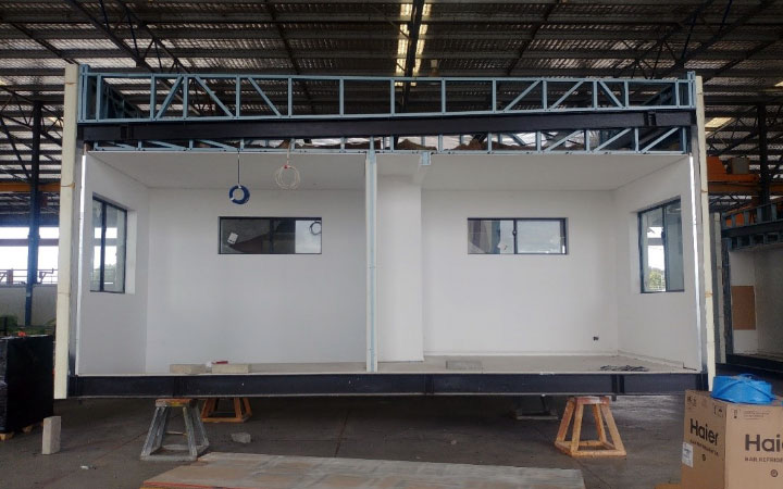 Prefab rooms under construction in a factory.