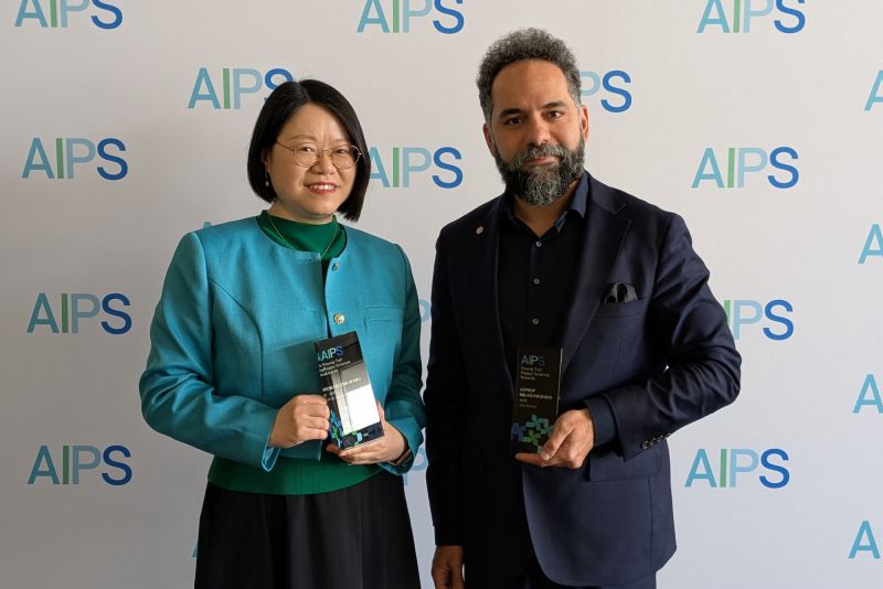 Two people standing, holding awards
