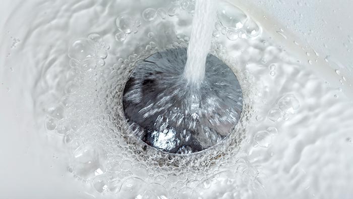 Close-up of stainless steel plug with water flowing over it