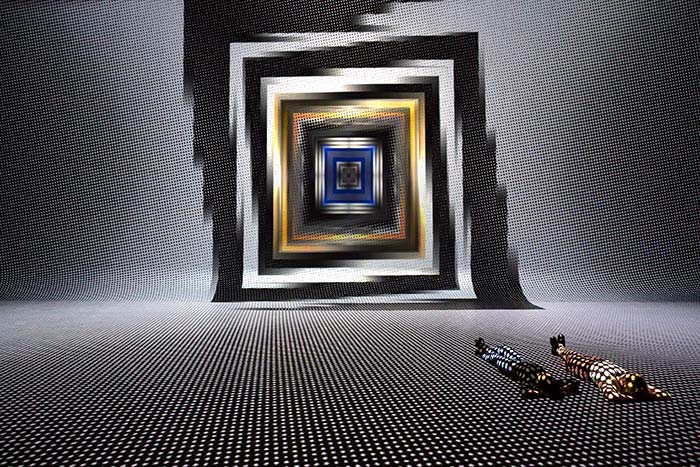 Two people lying on floor with dot grid projected over them and square spiral portal art on wall