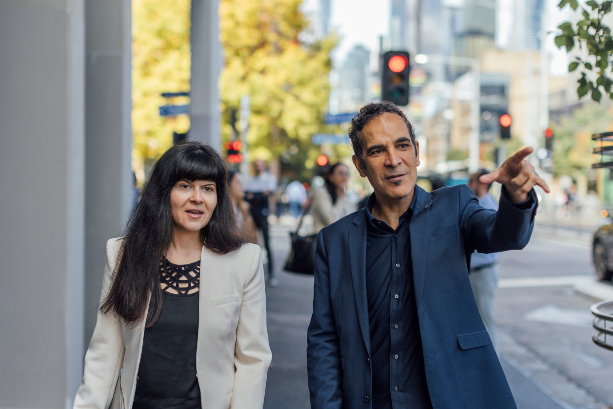 Two smiling people walk down a street 