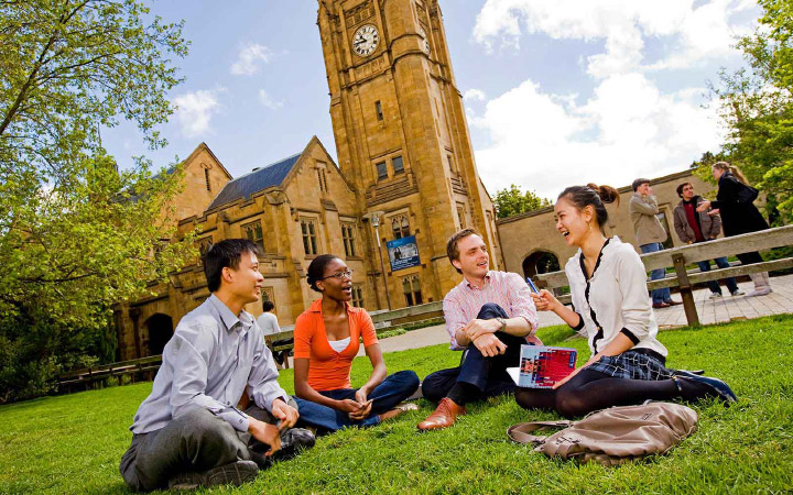 four students conversing while sitting on south lawn
