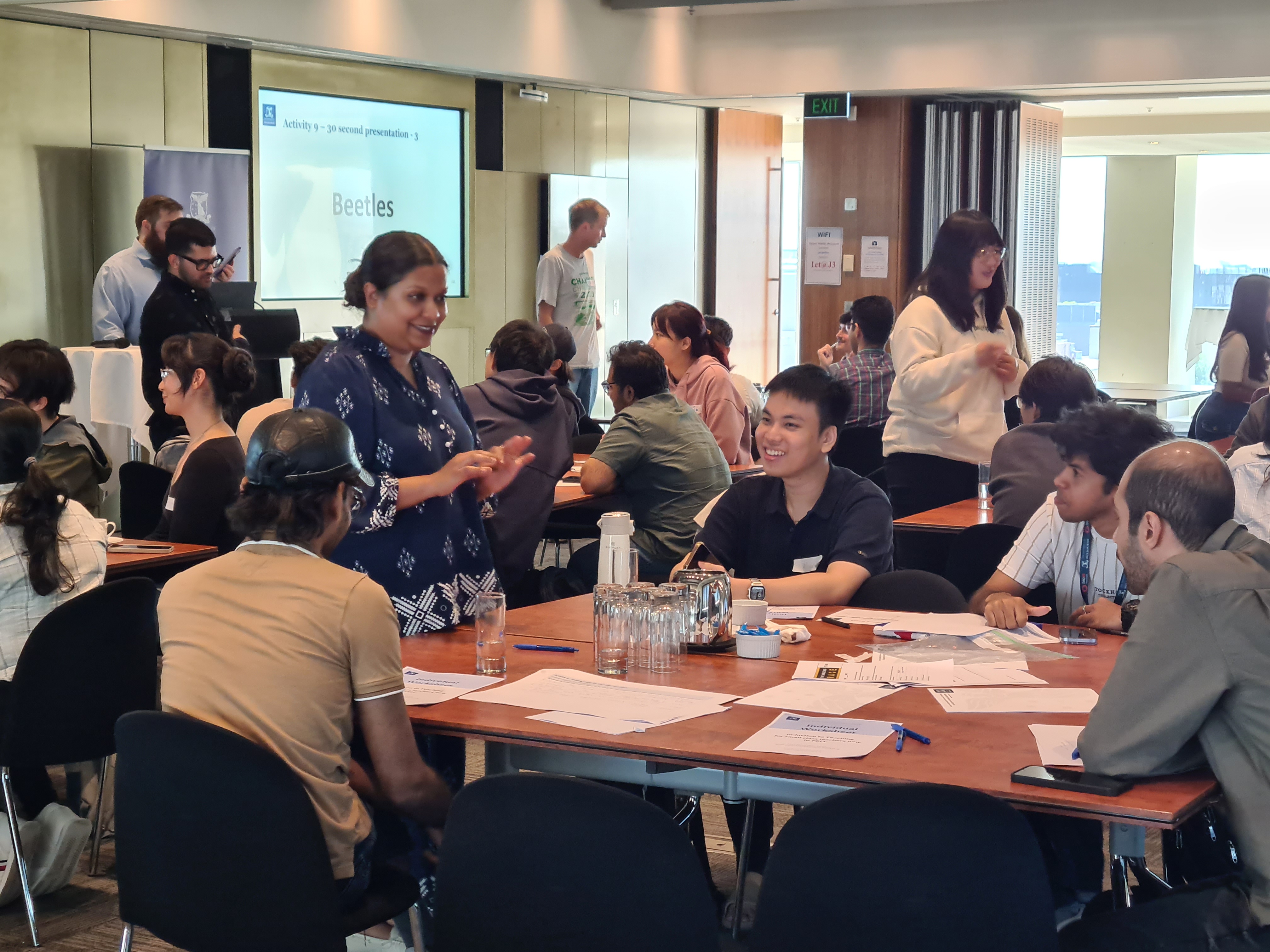 A group of new tutors participate in a group activity at a table, laughing and talking