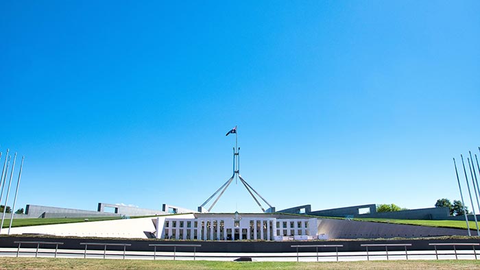 Parliament House in Canberra viewed from the front with blue sky behind it