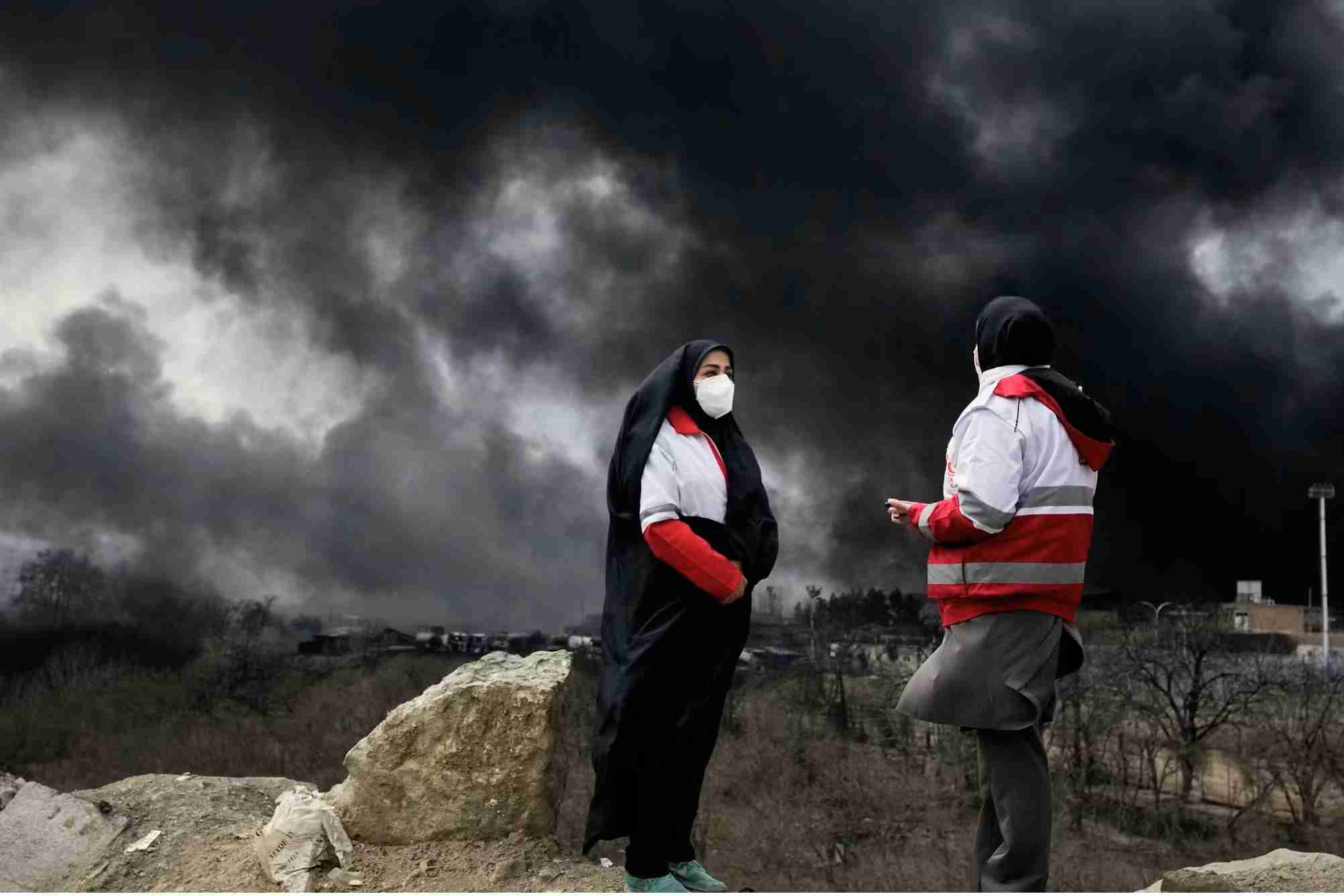Man and woman stand in cloud of black smoke.