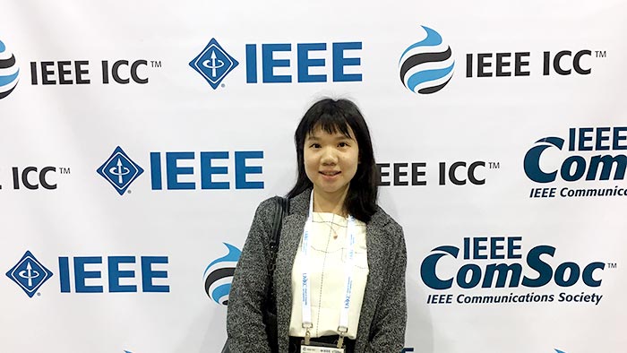 Dr Yuting Fang standing in front of wall with IEEE branding